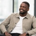 Daniel Kaluuya smiling during a seated interview, wearing a tan overshirt..