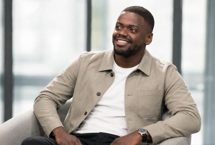 Daniel Kaluuya smiling during a seated interview, wearing a tan overshirt..