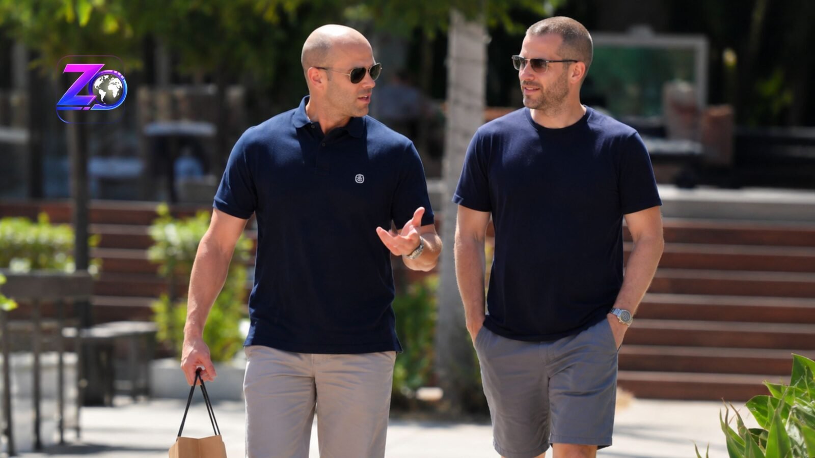 Hollywood actor Jason Statham walking and talking alongside a man in a casual outdoor setting.