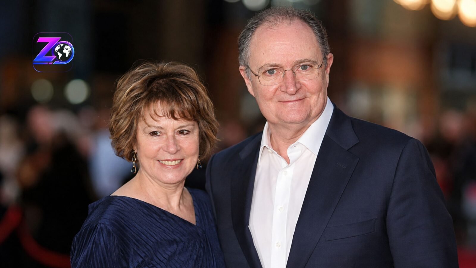 British actor Jim Broadbent smiling alongside his wife, artist Anastasia Lewis, at a public red carpet event.