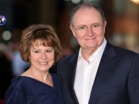 British actor Jim Broadbent smiling alongside his wife, artist Anastasia Lewis, at a public red carpet event.