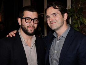 British comedian Jimmy Carr smiling alongside his Brother Colin Carr at a public event.