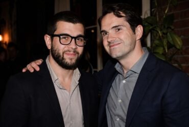 British comedian Jimmy Carr smiling alongside his Brother Colin Carr at a public event.