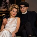 British singer Paloma Faith and French visual artist Leyman Lahcine sitting together on a dark green velvet sofa.