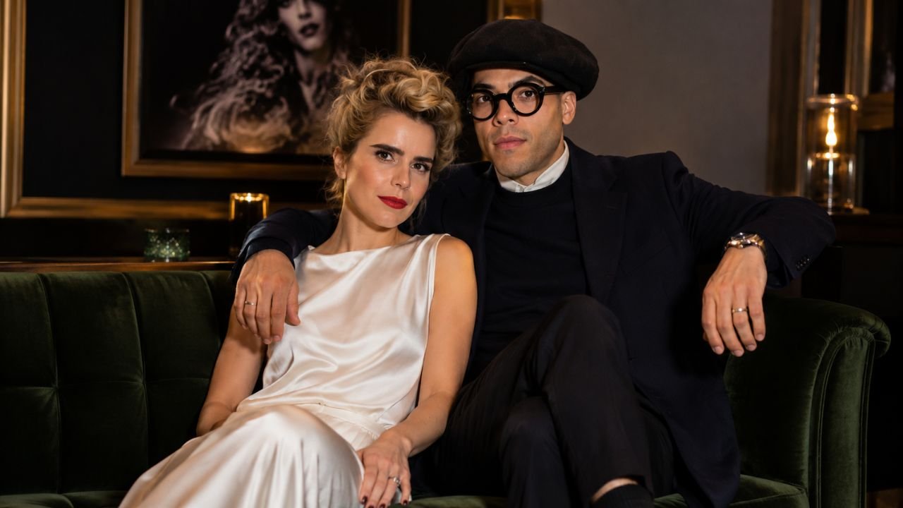 British singer Paloma Faith and French visual artist Leyman Lahcine sitting together on a dark green velvet sofa.