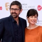 Documentary filmmaker Louis Theroux and his wife, executive producer Nancy Strang, smiling together on the red carpet at the Virgin Media British Academy Television Awards.