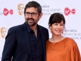 Documentary filmmaker Louis Theroux and his wife, executive producer Nancy Strang, smiling together on the red carpet at the Virgin Media British Academy Television Awards.