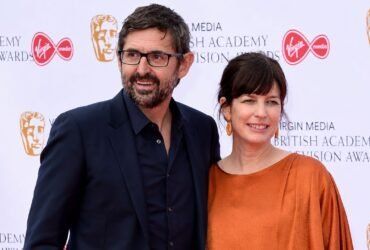 Documentary filmmaker Louis Theroux and his wife, executive producer Nancy Strang, smiling together on the red carpet at the Virgin Media British Academy Television Awards.