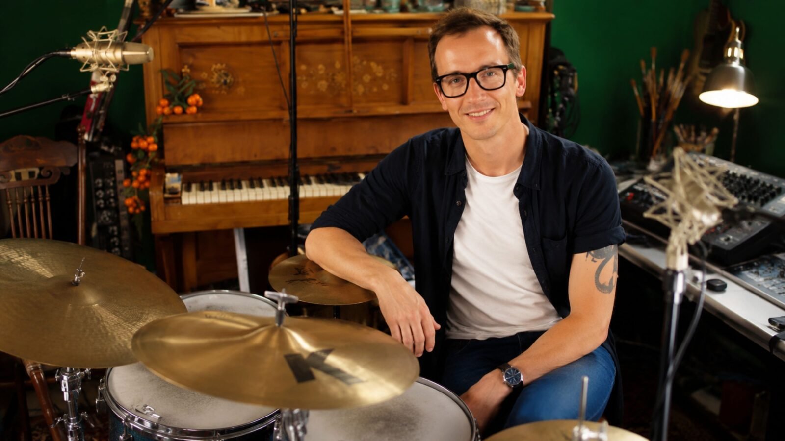 Professional drummer Luke Bullen smiling in his residential recording studio sitting next to his drum kit