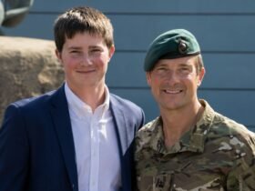 Marmaduke Grylls posing next to his father, Bear Grylls, who is dressed in military camouflage.