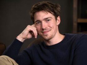 Portrait of emerging British actor Patrick Alwyn smiling gently while resting his head on his hand.