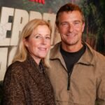 Shara Grylls smiling next to her husband, British adventurer Bear Grylls, at a public red carpet event.