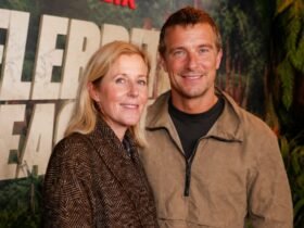 Shara Grylls smiling next to her husband, British adventurer Bear Grylls, at a public red carpet event.