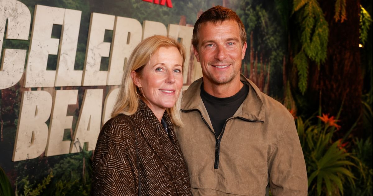Shara Grylls smiling next to her husband, British adventurer Bear Grylls, at a public red carpet event.