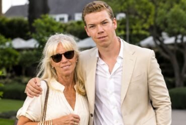 Actor Will Poulter standing outdoors next to his mother, Caroline Poulter, who is wearing sunglasses and a light-colored blouse.